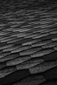 Close-up of black roof shingles forming an abstract textured pattern, emphasizing geometry and modern architecture.
